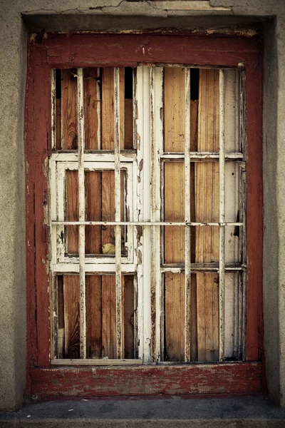 An old damaged window behind metal grating — Stock Photo, Image