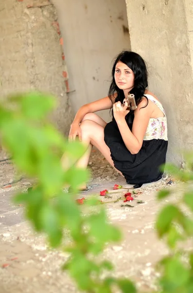 Attraktive junge Frau mit Waffe und Blumen — Stockfoto
