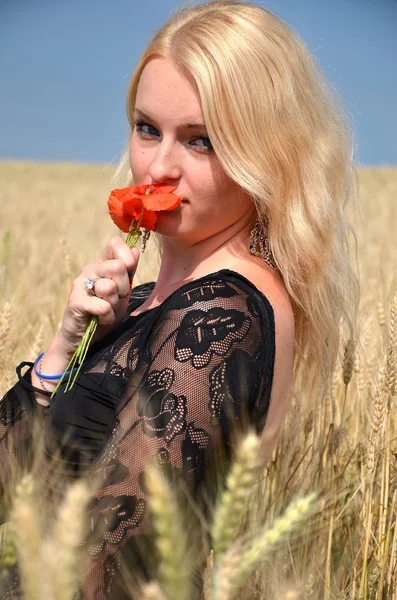 Donna bionda nel campo con fiore — Foto Stock