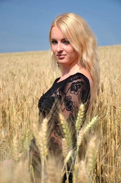 Blond kobieta w polu z kwiatem — Zdjęcie stockowe