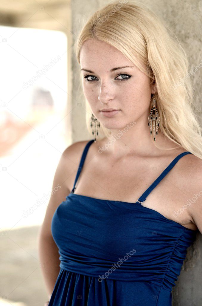 Young blonde woman posing in stylish blue dress