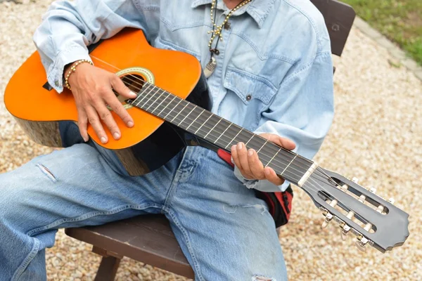 Homem está tocando uma guitarra acústica — Fotografia de Stock