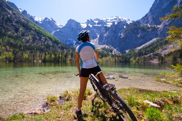 Kobieta yaung, jazda na rowerze obok alpejskiego jeziora — Zdjęcie stockowe