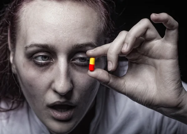 Mujer joven sosteniendo una píldora adicta . — Foto de Stock