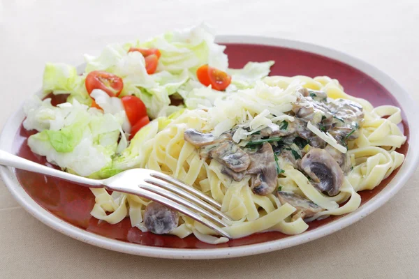 Tagliatelle with mushrooms and salad — Stock Photo, Image