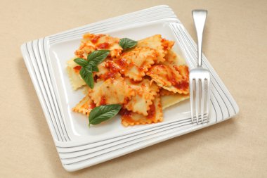 Plate of ravioli with a tomato sauce clipart