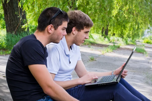 Młodzi ludzie siedzący na ziemi za pomocą laptopa — Zdjęcie stockowe