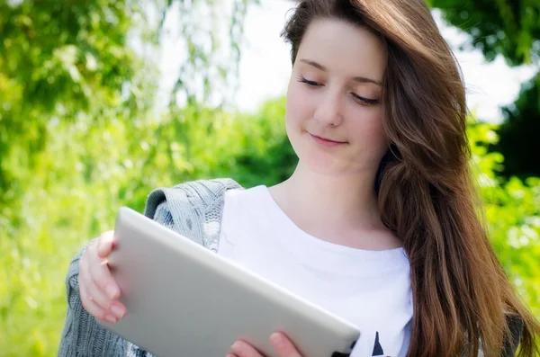 Junge Frau arbeitet im Park an einem Tablet — Stockfoto