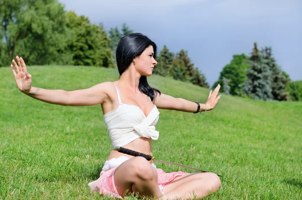 Mulher jovem atraente medita no gramado verde — Fotografia de Stock