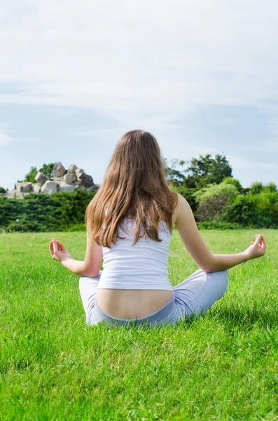 Vrouw mediteert op groene gazon op het park — Stockfoto
