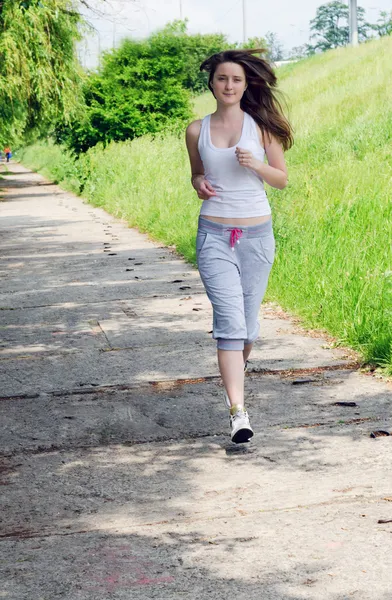 Young woman jogging through a park — Stock Photo, Image