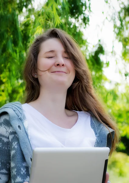 Jovem mulher trabalhando em um tablet no parque — Fotografia de Stock