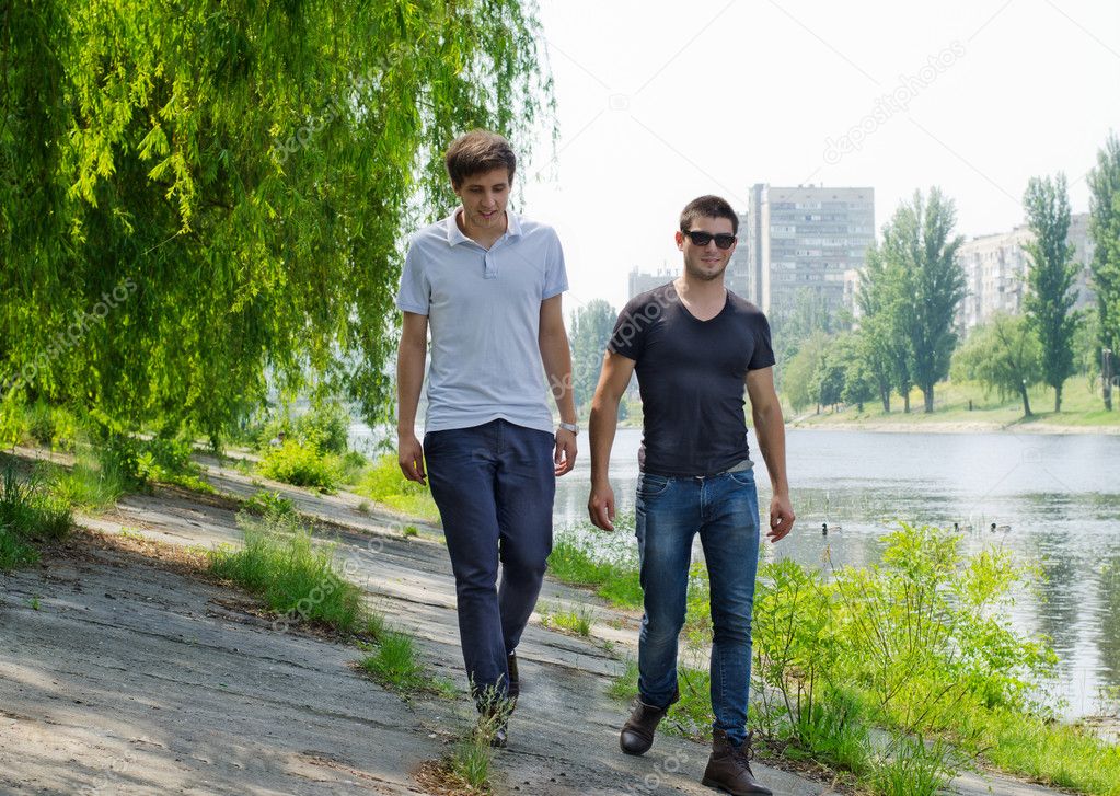 Two young men walking along a riverbank