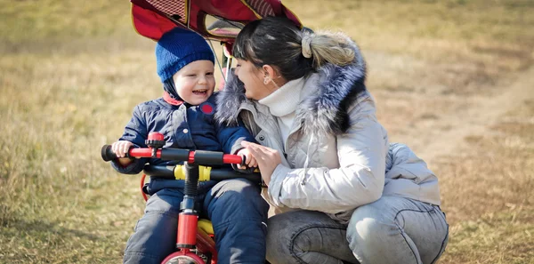 Mamma hjälper barn åka trehjuling — Stockfoto