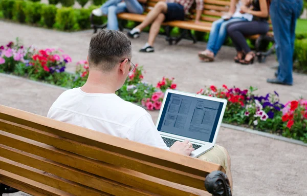 男子在一个公共公园中使用一台笔记本电脑 — 图库照片