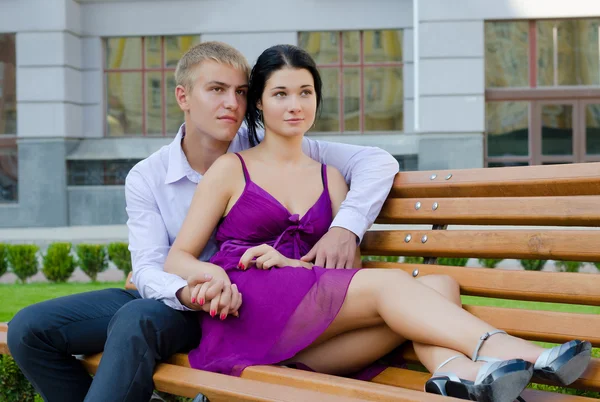 Romântico jovem casal sentado no banco — Fotografia de Stock