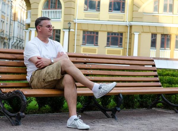 男子坐在城市的长椅上等待 — 图库照片