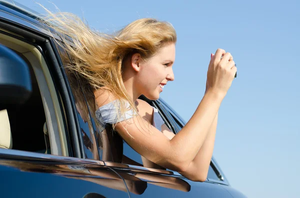 Woman in car taking photographs — Stockfoto