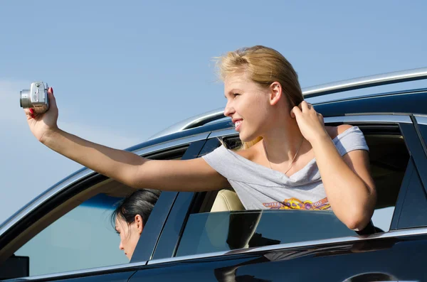 Young woman taking photos from a car — Stock Photo, Image