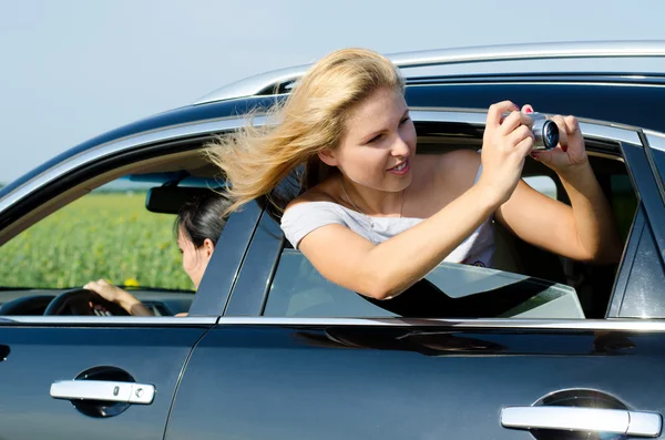 Attractive woman photographing from car window — Stock Photo, Image