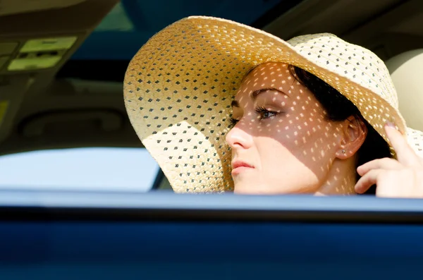 Kobieta w słomkowym kapeluszu siedzi w samochodzie — Zdjęcie stockowe