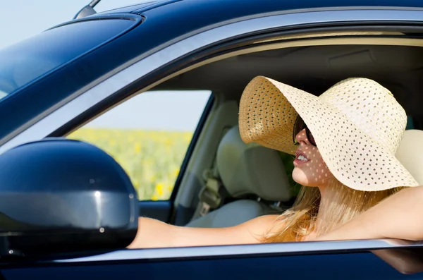 Woman in sunhat driving a car — Stock Photo, Image