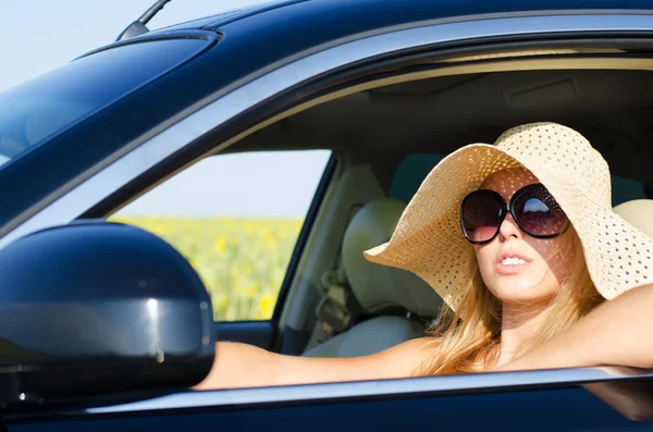 Woman driving in hat and sunglasses — Stockfoto