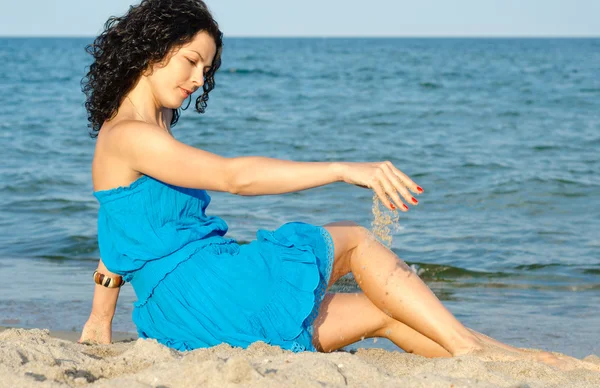 Женщина играет с морским песком — стоковое фото