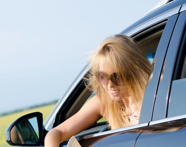 Blonde vrouw leunend uit een auto — Stockfoto