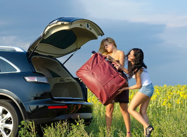 Frauen laden schwere Tasche ins Auto — Stockfoto