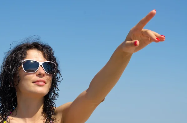 Femme en lunettes de soleil pointant vers le ciel — Photo