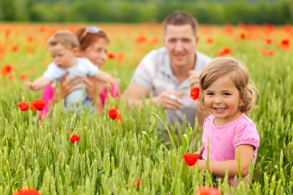 Young family in poppy field — Stock Photo, Image