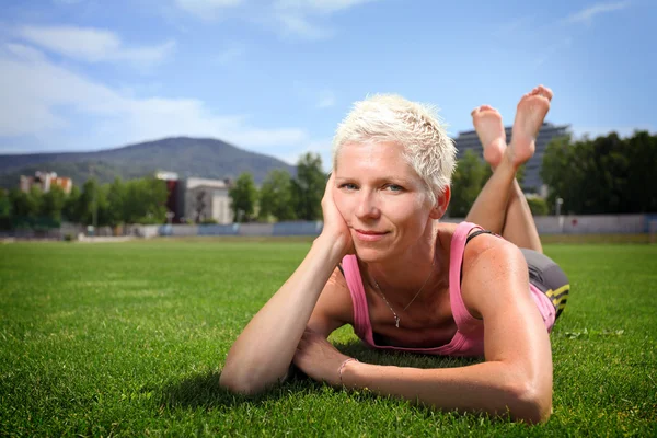 Actieve vrouw liggend op groen gras — Stockfoto