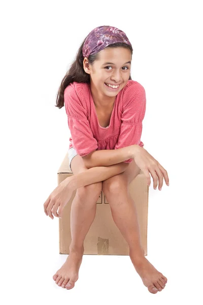 Jong meisje, zittend op een lege kartonnen doos. — Stockfoto