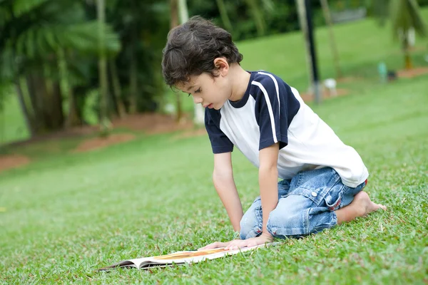 Jeune garçon appréciant son livre de lecture dans le parc extérieur — Photo