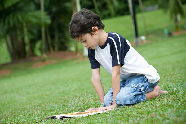 Jeune garçon appréciant son livre de lecture dans le parc extérieur — Photo