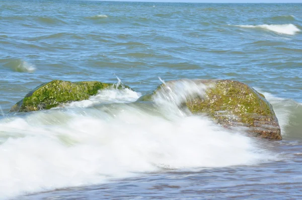 Duas pedras no mar envoltas em uma onda do mar — Fotografia de Stock