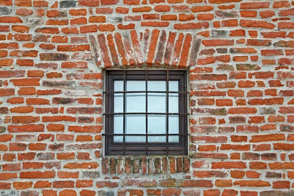 Ziegelmauer mit eisernem Gitterfenster eines antiken Gefängnisses — Stockfoto