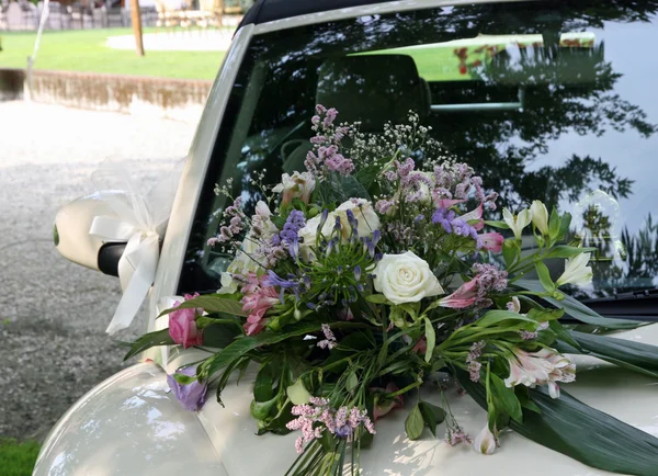 新婚夫妇的汽车的引擎盖上的花束 — 图库照片