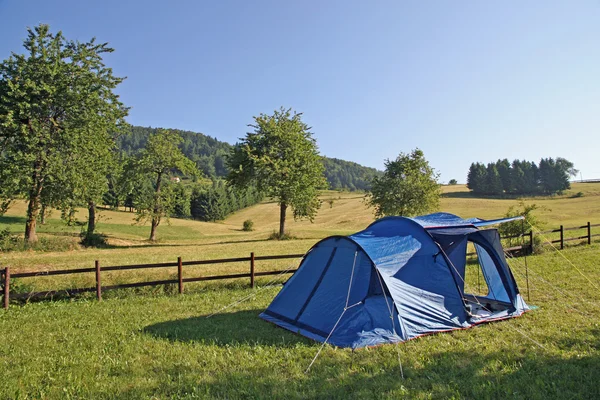 Kempingi niebieski namiot posadzonych pośród zielonej Łąki górskie — Zdjęcie stockowe
