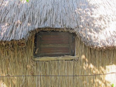 Wooden window set in an old hut of straw and hay clipart