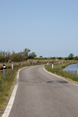 dar asfalt yol ve lagün ortasında bir eğri ile