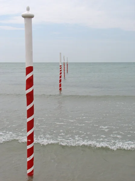 Red and white poles to delimit the rocks on the Sea — Stock Photo, Image