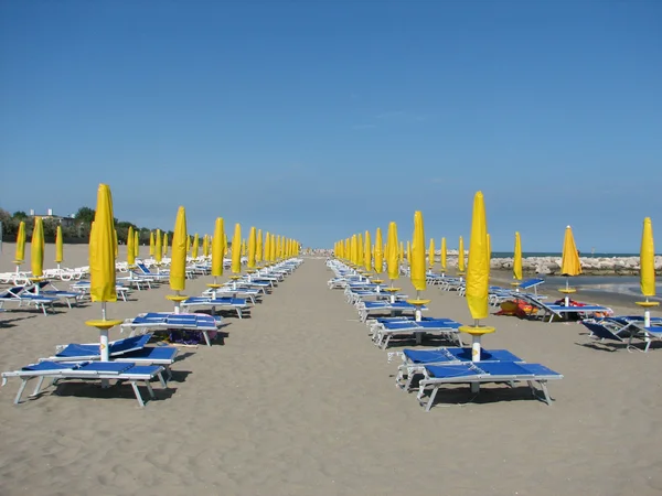 Series of Yellow Sun umbrellas and loungers and deckchairs on t — Stock Photo, Image
