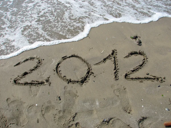 Escrito 2012 en la orilla del mar está a punto de ser borrado por la w — Foto de Stock