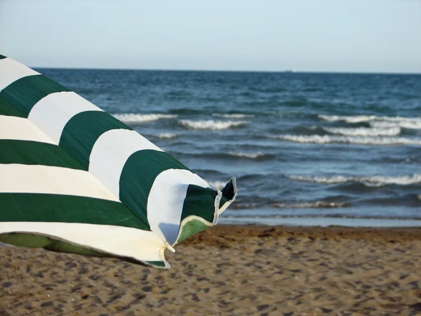 Paraguas rayado verde y blanco por la orilla del mar — Foto de Stock