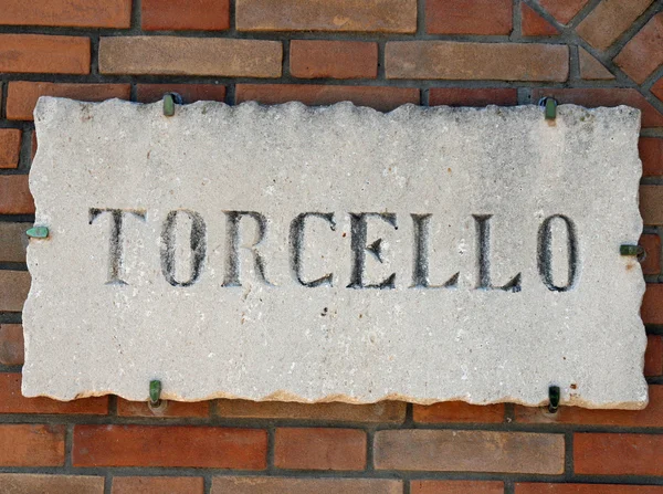 Escrito TORCELLO na lápide de mármore em uma parede de tijolo perto — Fotografia de Stock