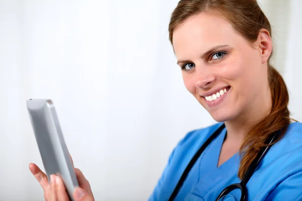 Красивая блондинка-медсестра улыбается с планшетным ПК — стоковое фото
