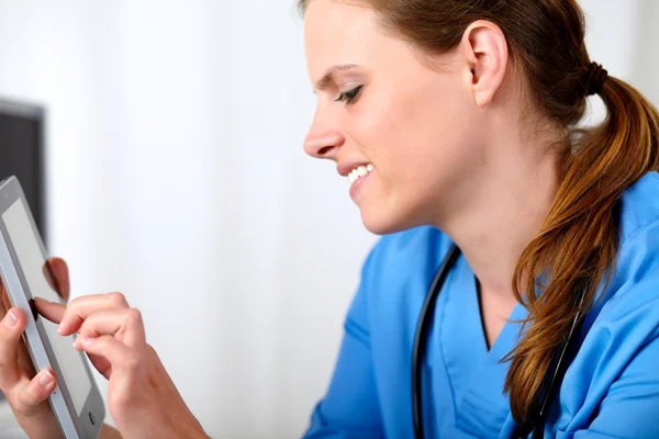 Дружелюбная медсестра улыбается планшетным компьютером — стоковое фото