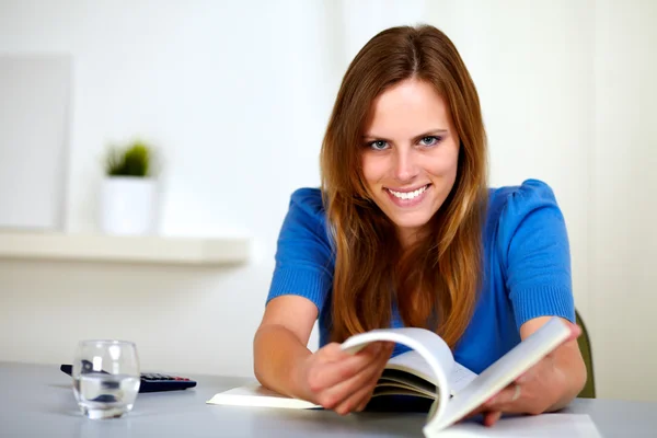 Милая молодая женщина улыбается и читает книгу — стоковое фото